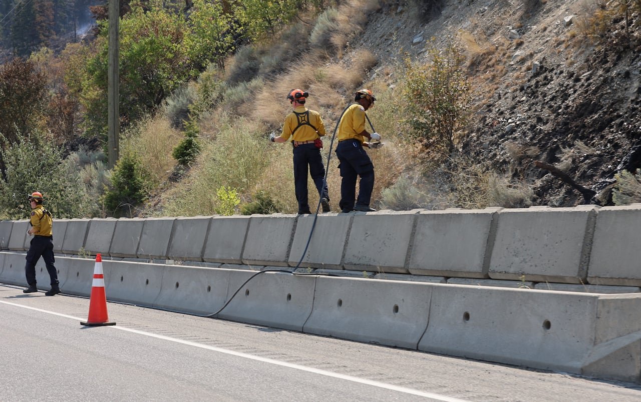 Firefighters working near Summerland. They are wearing yellow and using hoses.
